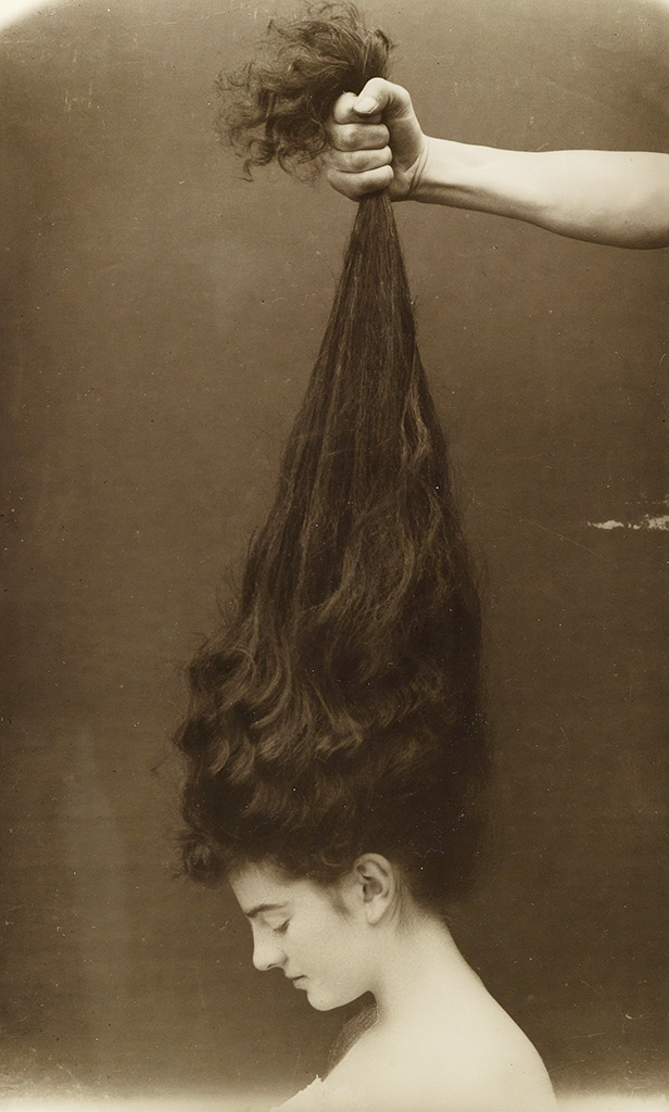 Hand grasping a beautiful young woman's long, dark hair. 'Bromide print, Circa 1910