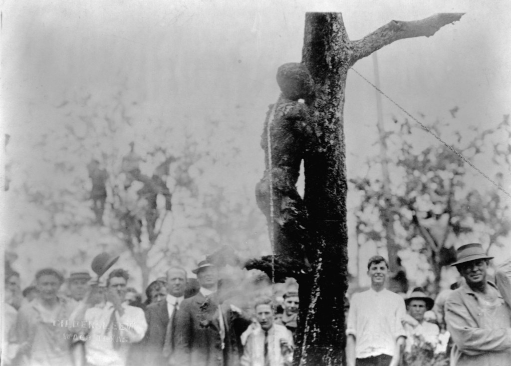 15 May 1916, Waco, Texas, USA --- A crowd of people stands to watch the lynching by burning of Jesse Washington whose charred corpse leans chained to the trunk of a tree. Waco, Texas. --- Image by © CORBIS